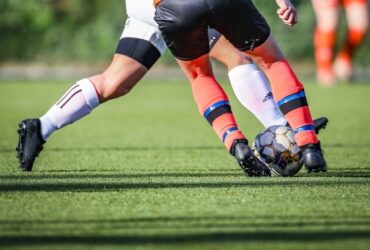 Fotballspillere kjemper om ballen på en grønn kunstgressbane
