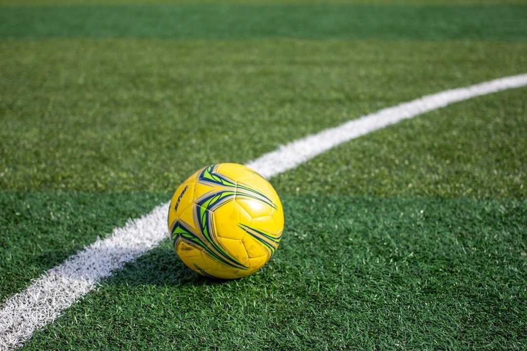 Gul fotball ligger på en hvit linje på kunstgressbanen